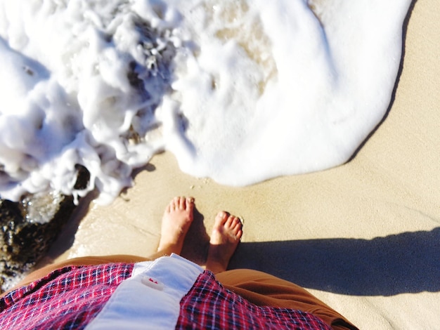 Foto sección baja de un hombre de pie en la playa