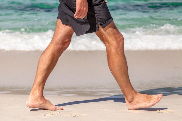 Foto sección baja de un hombre de pie en la playa