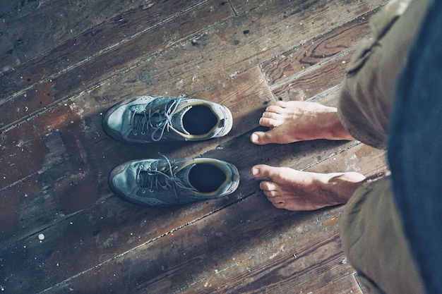 Sección baja de un hombre de pie con zapatos en el suelo de madera dura