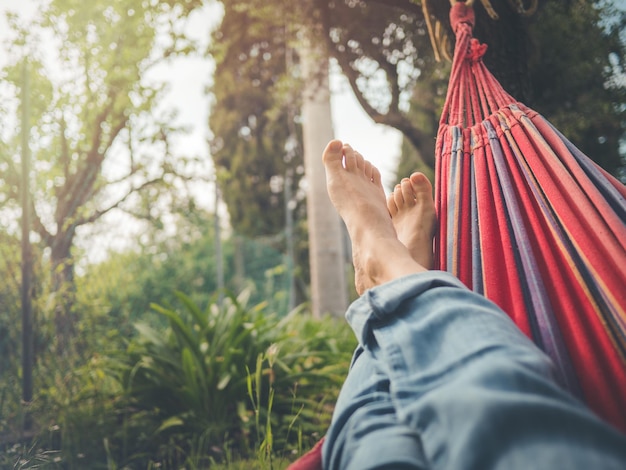 Foto sección baja de un hombre relajándose en una hamaca en el bosque