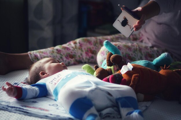 Foto sección baja de la madre jugando con el bebé mientras está sentada en la cama en casa