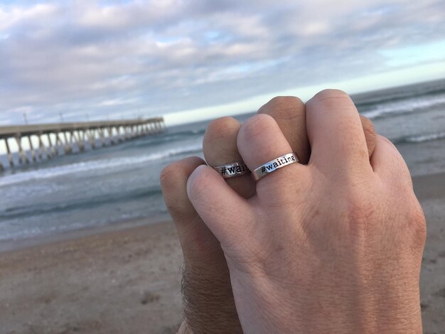 Foto sección baja de la mano de la persona contra el mar contra el cielo