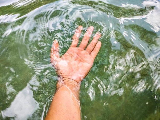 Foto sección baja de la mano de la persona en el mar