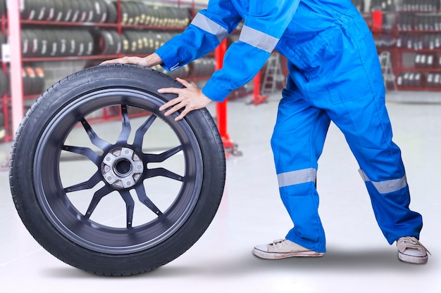 Foto sección baja de mecánico reparando neumáticos en un taller de reparación de automóviles