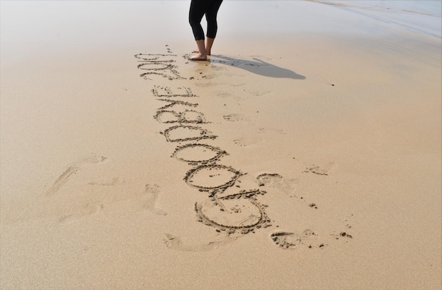 Foto sección baja de una mujer en la arena de la playa