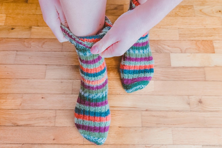 Foto sección baja de una mujer con calcetines de varios colores en el suelo