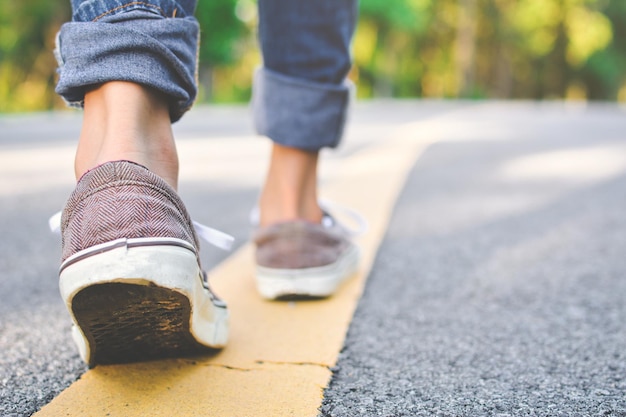 Sección baja de una mujer caminando por la carretera