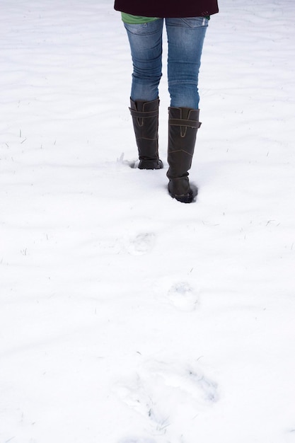 Foto sección baja de una mujer caminando en la nieve