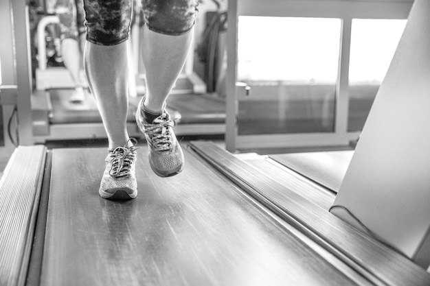 Foto sección baja de una mujer corriendo en una cinta de correr en el gimnasio