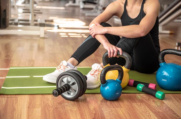 Foto sección baja de una mujer con equipo de ejercicio en el gimnasio