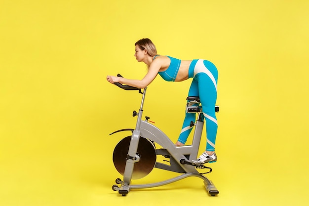 Sección baja de una mujer haciendo ejercicio con un juguete sobre un fondo amarillo
