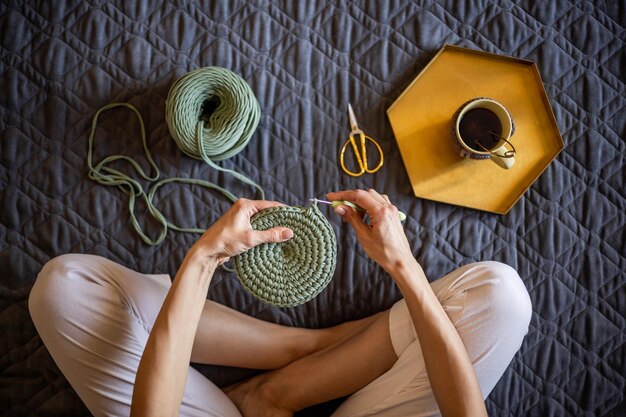 Foto sección baja de una mujer haciendo ganchillo en casa