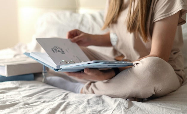 Sección baja de una mujer leyendo un diario sentada en la cama en casa