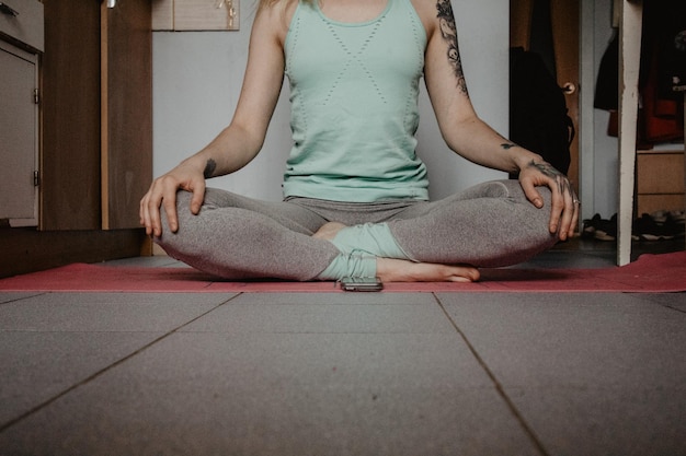 Foto sección baja de una mujer meditando mientras está sentada en casa