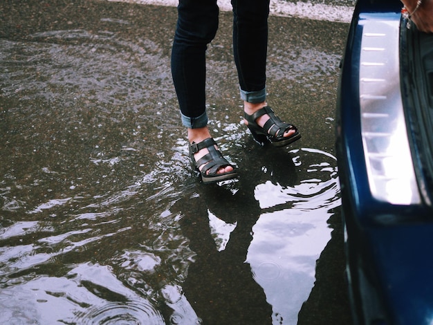 Foto sección baja de una mujer de pie en un charco