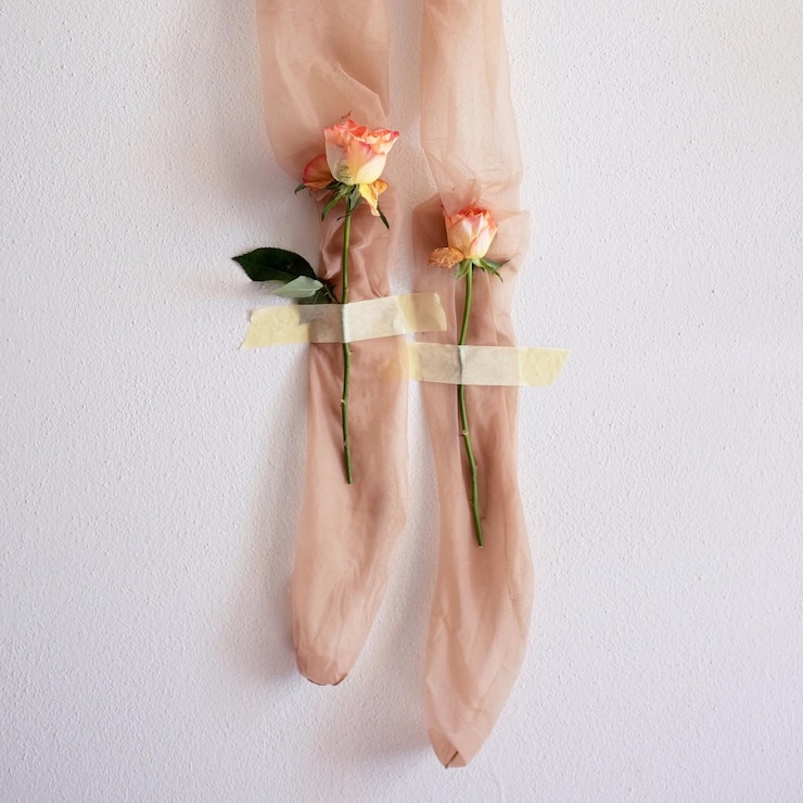 Foto sección baja de una mujer de pie junto a una planta con flores