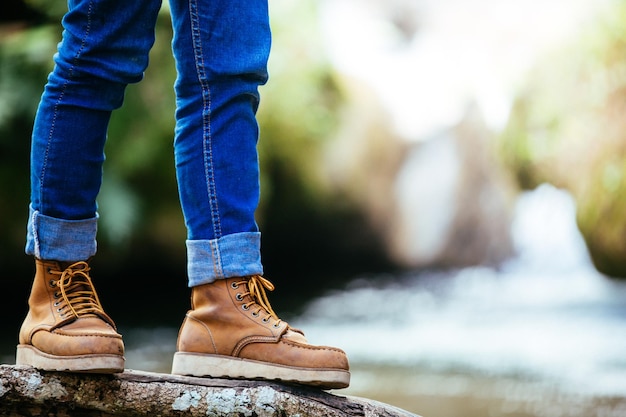 Foto sección baja de una mujer de pie en madera contra una cascada