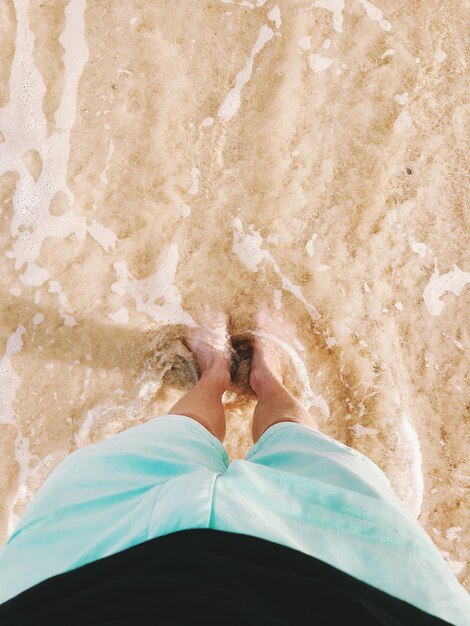 Foto sección baja de una mujer de pie en la playa