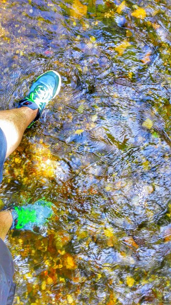 Foto sección baja de una mujer de pie en una roca en un río