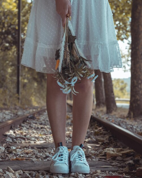 Foto sección baja de una mujer de pie en la vía del ferrocarril