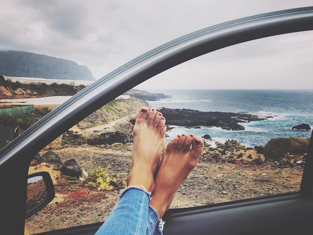 Foto sección baja de una mujer con los pies en la puerta del coche