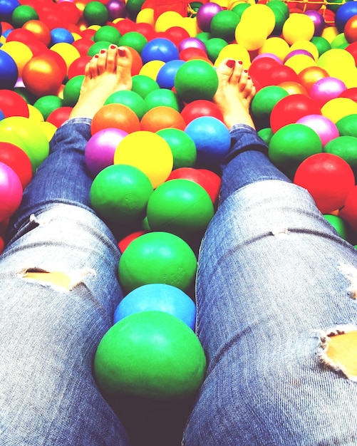 Foto sección baja de la mujer en la piscina de bolas multicolores