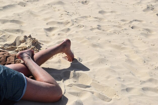 Foto sección baja de una mujer relajándose en la arena de la playa