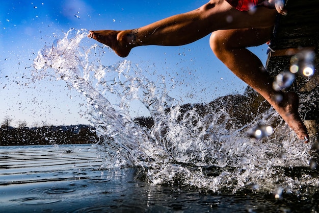 Foto sección baja de la mujer salpicando agua en el lago