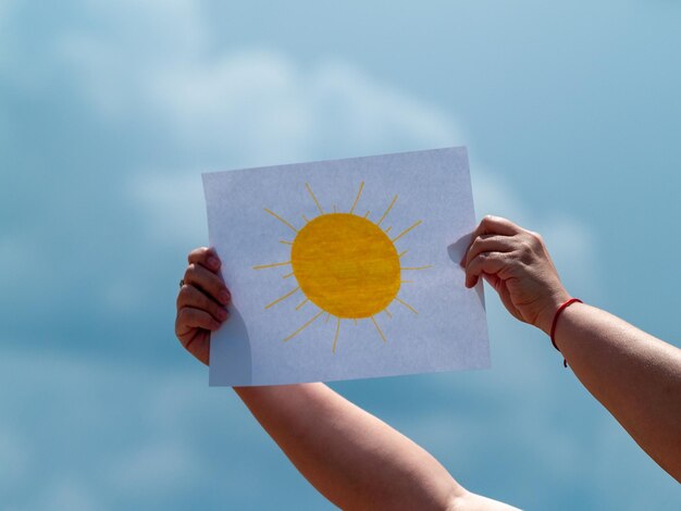 Foto sección baja de una mujer sosteniendo papel contra el cielo