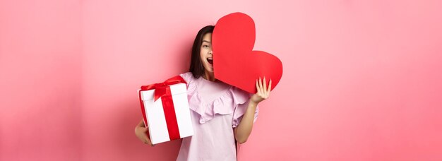 Foto sección baja de una mujer sosteniendo un regalo contra un fondo amarillo