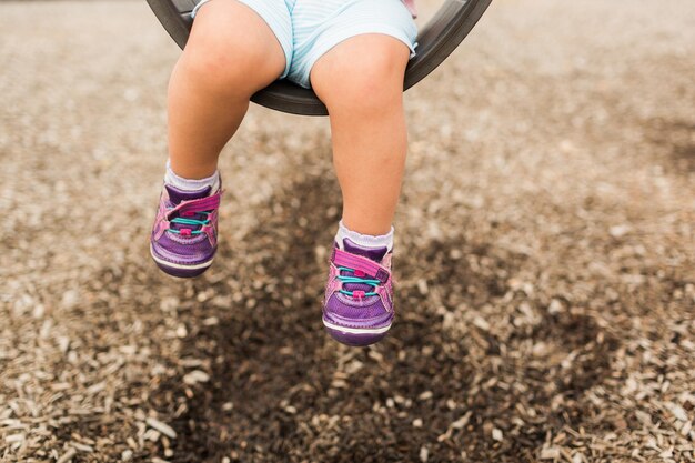 Foto sección baja de una niña balanceándose en el patio de recreo