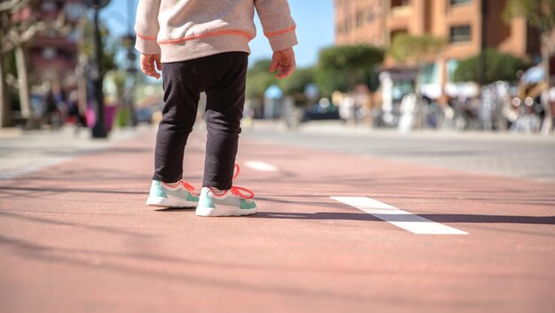 Foto la sección baja de la niña de pie en el sendero de la ciudad