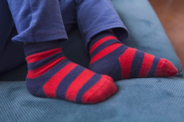 Sección baja de un niño con calcetines en el sofá en casa