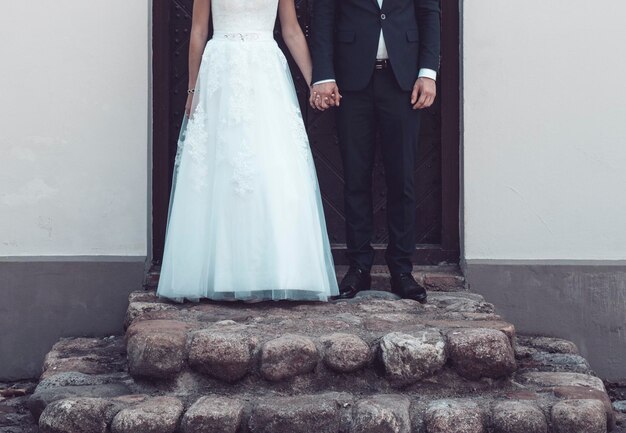 Foto sección baja de la novia y el novio tomados de la mano mientras están de pie en los escalones