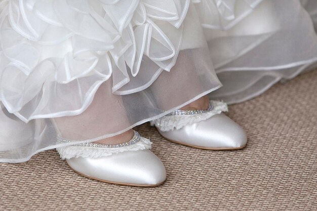 Foto sección baja de la novia con zapatos en la alfombra