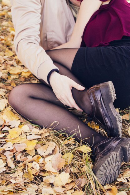 Foto sección baja de una pareja romántica en un campo cubierto de hojas