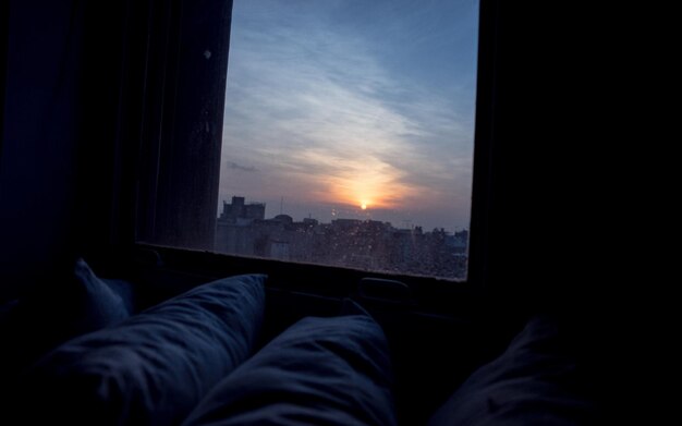 Foto sección baja de una persona contra el cielo vista a través de una ventana de vidrio