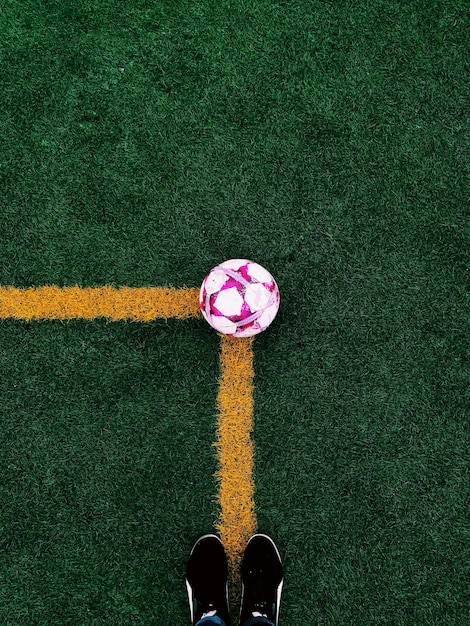 Foto sección baja de una persona de pie en un campo de fútbol con una pelota