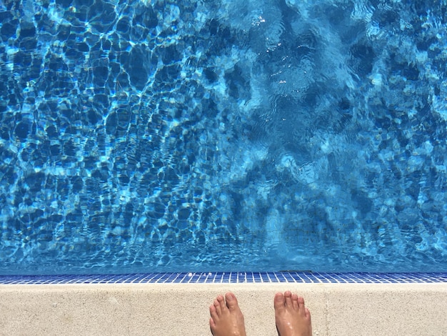 Foto sección baja de una persona de pie junto a la piscina