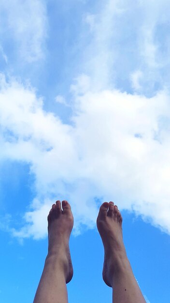 Foto sección baja de una persona relajándose contra el cielo azul