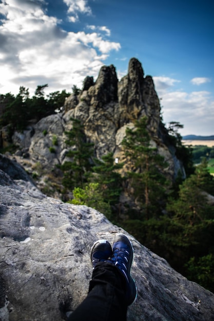 Foto sección baja de una persona en una roca contra las montañas y el cielo