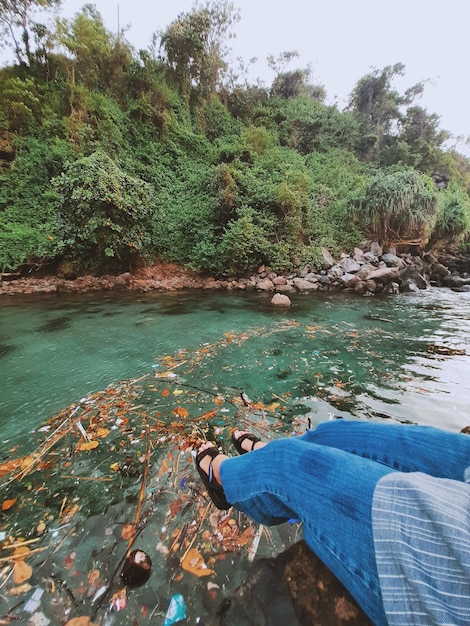 Foto sección baja de una persona en una roca junto al lago