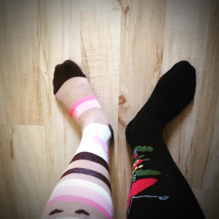 Foto sección baja de una persona con varios calcetines de colores en el piso de la casa