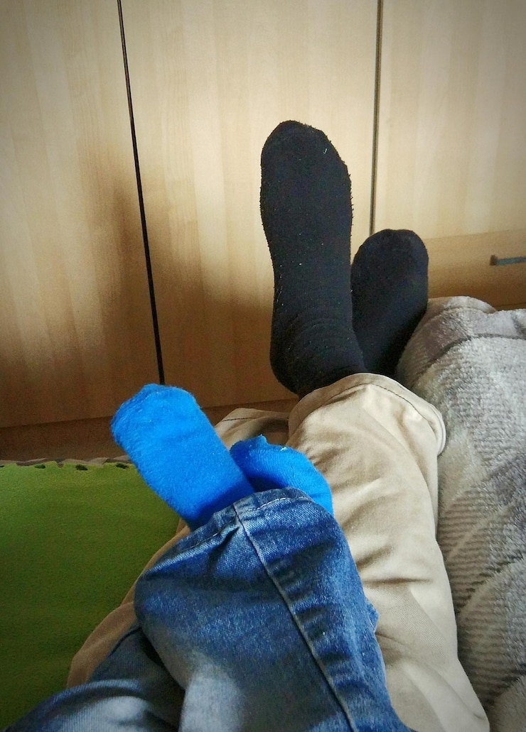 Foto sección baja de personas con calcetines acostadas en la cama en casa