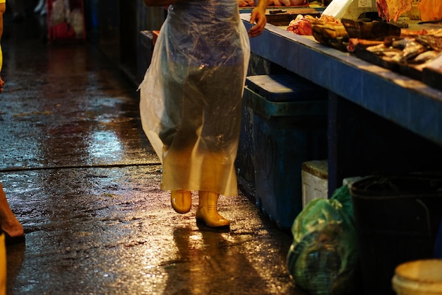 Foto sección baja de personas caminando en el mercado callejero durante la temporada de lluvias