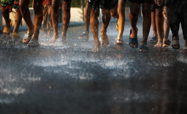 Foto sección baja de personas corriendo en la calle mojada