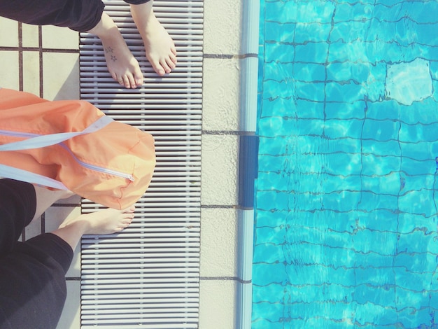 Foto sección baja de personas de pie junto a la piscina