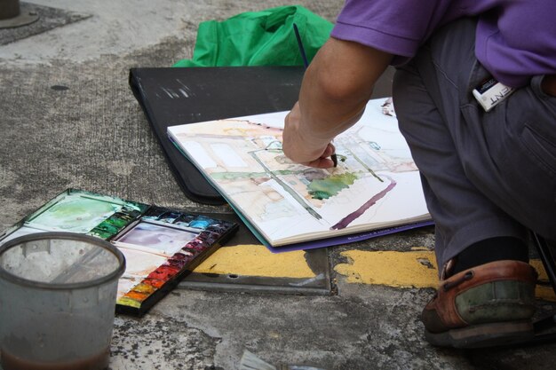 Foto sección baja de la pintura del hombre en el libro en el sendero