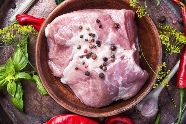 Sección de carne de cerdo cruda con especias en una vieja mesa de madera