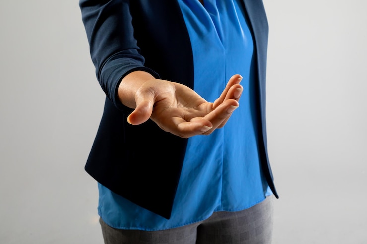 Foto sección intermedia de una empresaria sosteniendo un objeto invisible contra un fondo gris